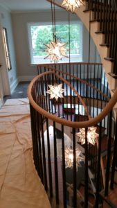 large spiral staircase with oak handrails and black balusters. multiple star shaped lights hang in the center of the staircase.