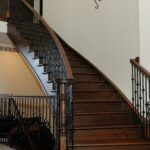 Curved dark stained staircase with black iron balusters