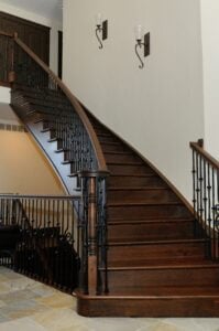 Curved dark stained staircase with black iron balusters