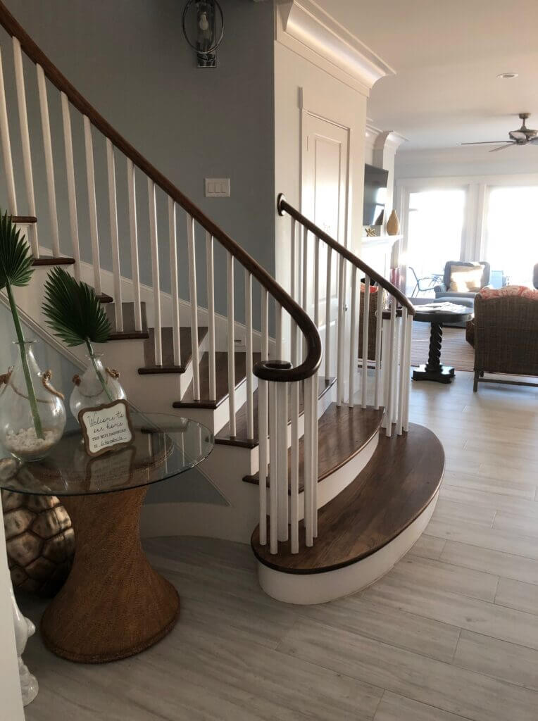 the base of a stained and painted wood staircase with a bowed starter step