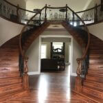 Entry of a home with a pair of matching curved ornate wooden staircases.