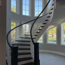 Beautiful 180 degree curved staircase with dark stained newel posts and treads.