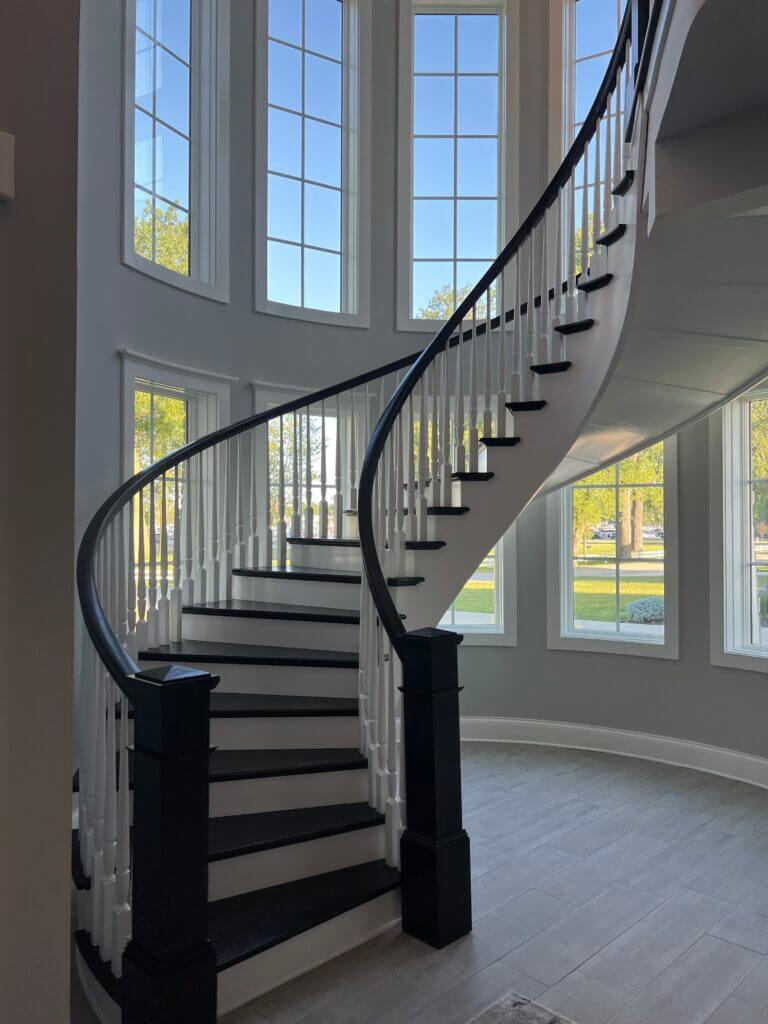 Beautiful 180 degree curved staircase with dark stained newel posts and treads.