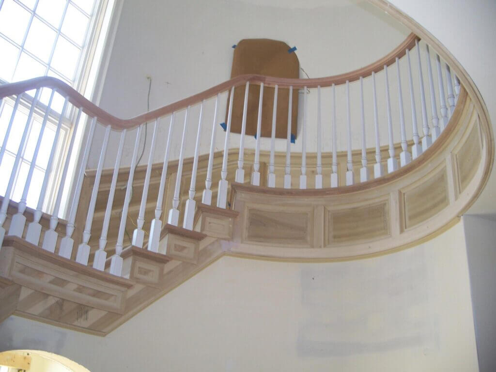 Large circular staircase with light stained wood and painted wood parts