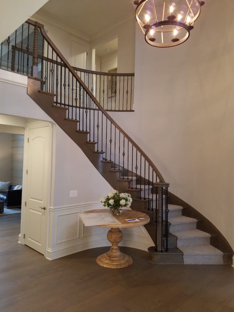 Curved wooden staircase with carpet runners and iron balusters