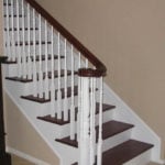 Traditional wooden staircase with white painted newel posts and dark stained railing and treads