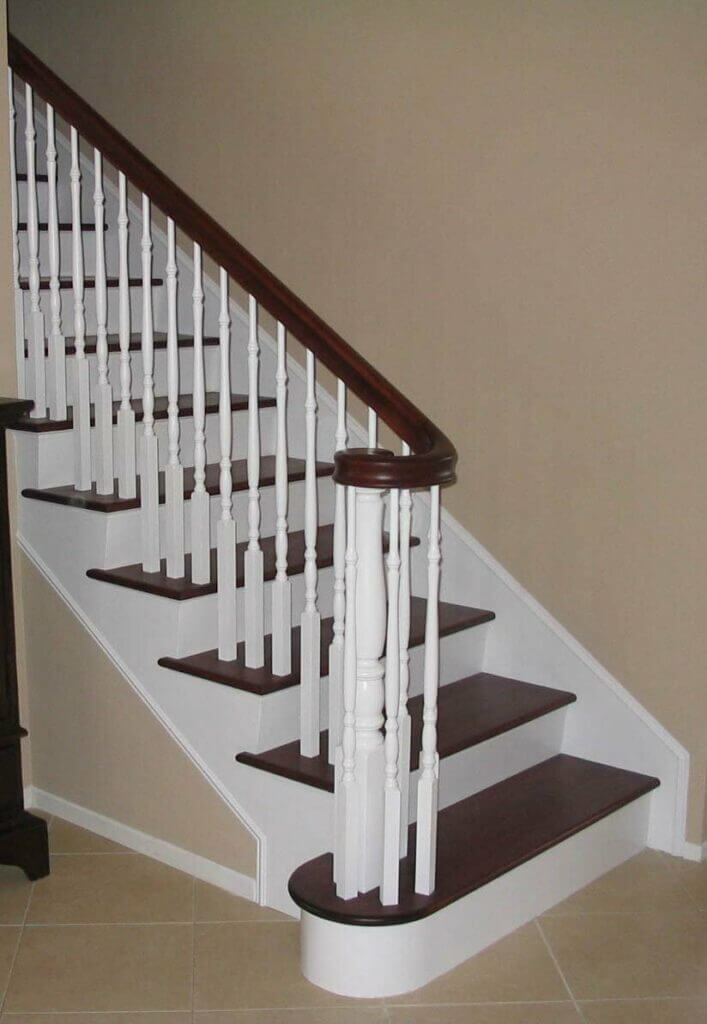 Traditional wooden staircase with white painted newel posts and dark stained railing and treads